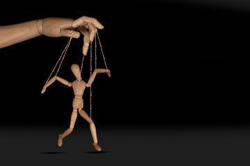 Wooden puppet doll, obeying master  hand pulling the strings of dancing marionette