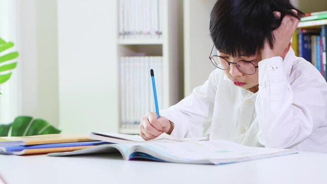 A young student concentrating on his schoolwork and studies, studying hard despite being bored and tired.
