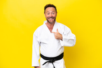 Middle age caucasian man doing karate isolated on yellow background with surprise facial expression © luismolinero