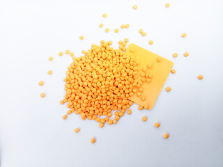 Orange masterbatch plastic granules, polymer carries colorful pigments poured into a white...