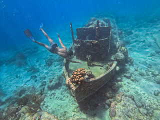 Freediver exploring sunken shipwreck in clear tropical waters