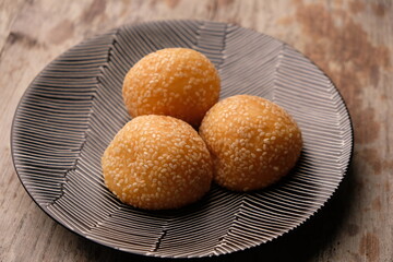 onde-onde or sesame balls are sweet snacks filled with green beans. sesame balls on a white ceramic plate.