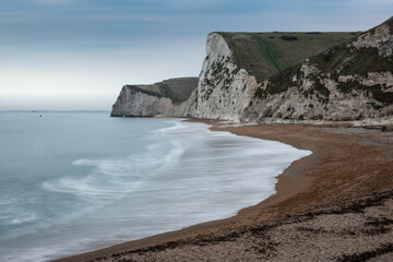 Beautiful atmospheric landscape image of rock arch and cliffs on Jurassic Coast in England during Winter sunset