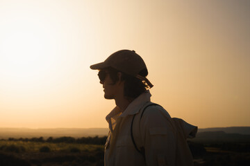 Profile of a tourist wearing sunglasses and a cap looking at the sunset in bardenas reales, navarra, spain