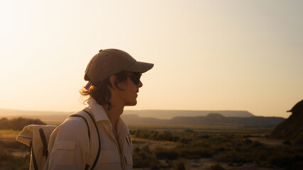 Young man with backpack enjoying sunset view in bardenas reales desert, navarra, spain