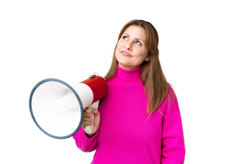 Naklejka premium Middle age woman over isolated background holding a megaphone and looking up while smiling