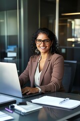 Fototapeta premium Young Indian businesswoman professional employee using pc doing online banking analysing at workplace. Latin hispanic middle-aged business woman working on laptop computer in modern office.