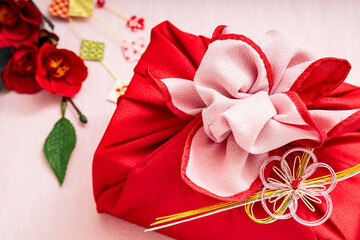 赤色の風呂敷包みと椿と和小物｜背景ピンク