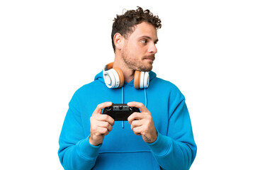 Brazilian man playing with a video game controller over isolated chroma key background looking to the side © luismolinero