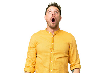 Brazilian man over isolated chroma key background looking up and with surprised expression