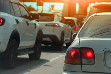 Fototapeta premium Rear side of car with turn on brake light. Traffic of car line up in a queue during time of business or travel trip. Background of Concrete bridge pillars with orange sun.