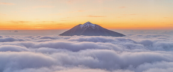 Naklejka premium Mountain peak rising above clouds at sunrise, nature's grandeur