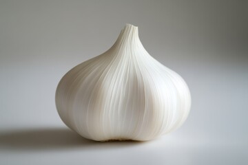 A close-up of a white garlic bulb, showcasing its smooth texture and distinct shape against a neutral background.
