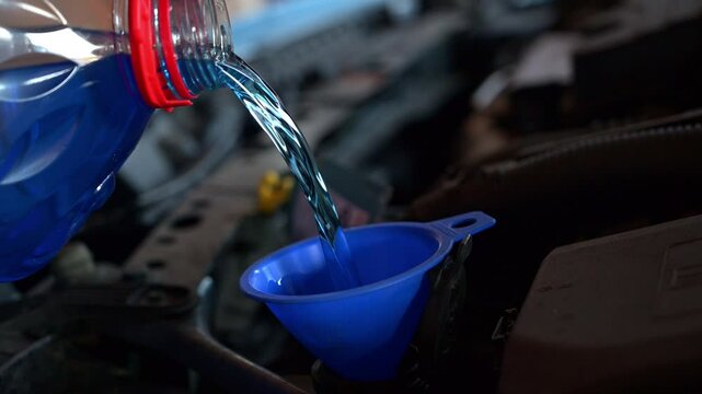 Nachf&uuml;llen von Scheibenfrostschutz in den Tank des Spritzwasserbeh&auml;lters im Motorraum des Autos