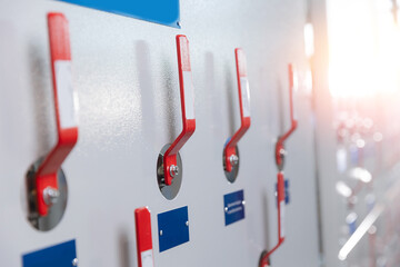 Industrial factory control panel with red levers and sunlight