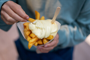 Boy dipping french fries in mayonnaise, enjoying classic street food treat