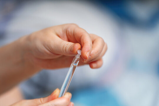 woman's hand carefully removes a plastic cap from a glass vial containing medication for treating warts and papillomas