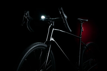 Black gravel bike with illuminated light on dark background