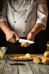 A chef expertly slices a potato with precision in a rustic kitchen, surrounded by fresh produce and tools, highlighting the art of culinary preparation and dedication to quality