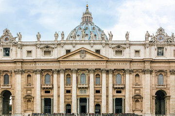 A large building St. Peter's Church of Vatican in Italy with a blue dome and a cross on top. The building has a lot of statues on it