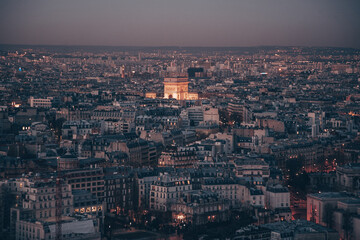 Obraz premium A city skyline of Paris with a tall building in the middle. The sky is dark and the city is lit up