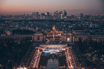 A Paris city with a large building in the center. The building is lit up at night. There are many cars on the street