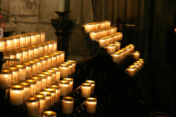 A candle holder with many candles in it. The candles are lit and are in a row