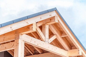 Obraz premium Construction of a modern wooden roof highlighted under a clear blue sky during daylight