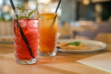 Two mocktails, Cinderella with grenadine and raspberry lemonade, on a wooden table in soft focus