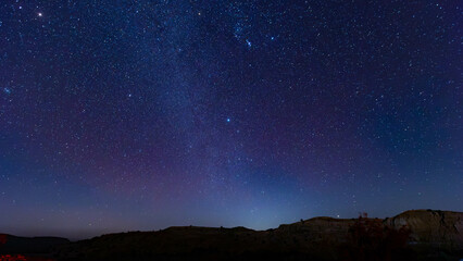 Fototapeta premium Night sky view over serene landscape showcasing stars and constellations in a clear atmosphere during dusk