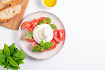 Delicious Italian caprese salad with sliced mozzarella, tomatoes, basil, and bread on background. 