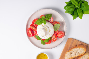 Delicious Italian caprese salad with sliced mozzarella, tomatoes, basil, and bread on background. 