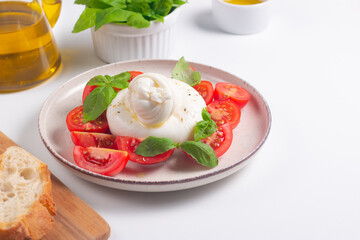 Delicious Italian caprese salad with sliced mozzarella, tomatoes, basil, and bread on background. 