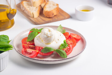 Delicious Italian caprese salad with sliced mozzarella, tomatoes, basil, and bread on background. 