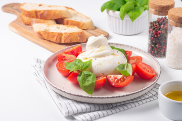 Delicious Italian caprese salad with sliced mozzarella, tomatoes, basil, and bread on background. 