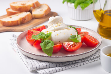 Delicious Italian caprese salad with sliced mozzarella, tomatoes, basil, and bread on background. 