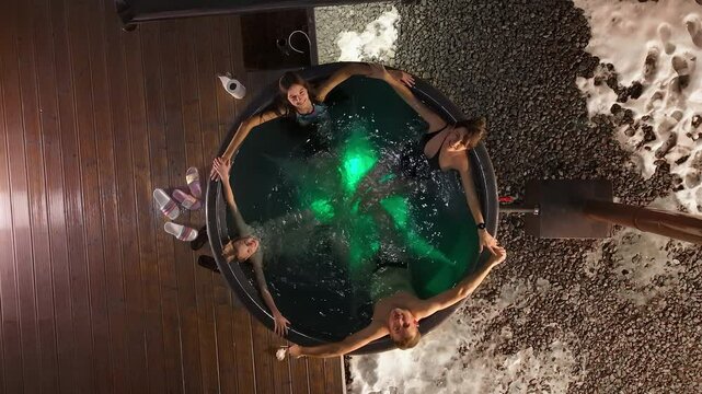 Aerial top view Family in Outdoor Hot Tub, A Family enjoying a warm hot tub outside in snowy surroundings at night.