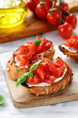 Cherry tomatoes and cream cheese bruschettas with fresh basil leaves on white wooden background 