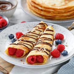 Crepes or thin pancakes with cottage cheese filling, fresh berries and chocolate sauce , sprinkled with nuts