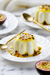Panna cotta dessert with fresh passion fruit sauce on white wooden background