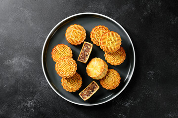 Traditional Chinese dessert. Homemade baked mooncakes filled with nuts and dried fruits, Chinese Mid-Autumn Festival food. black background, top view