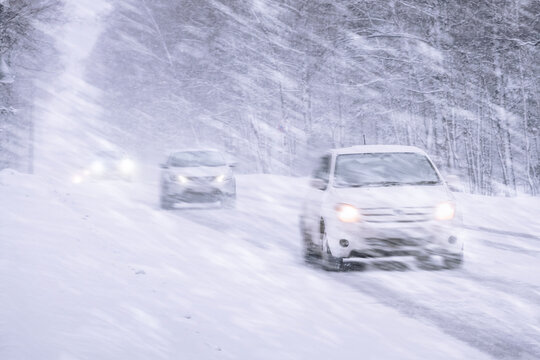 Winter snowstorm, snowfall and ice on roads with strong winds. Poor visibility and dangers on the road, driving safety in winter in bad weather. Cars Navigating Through Heavy Snowstorm Conditions That