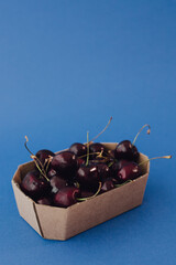 Fresh cherry in cardboard packaging on background. Healthy raw food, dessert without sugar and...