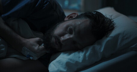 Patient lies on the hospital cot, trembling uncontrollably, due to a fever.