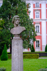 A Chopin's statue on a pedestal in a park before a building
