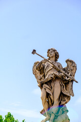 Obraz premium A statue of an angel with a trident stands against a blue sky