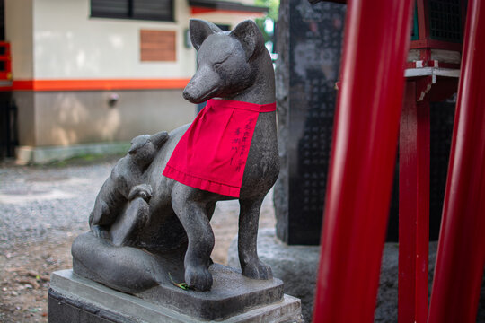 Kitsune Statue with Red Bib at Japanese Inari Shrine, Fox Guardian - Powered by Adobe