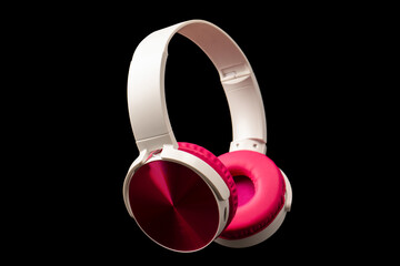 Pink and white headphones isolated on a black background.