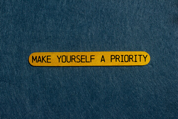 Make yourself a priority message written on yellow wooden stick with gray background. Conceptual make yourself a priority symbol. Copy space.