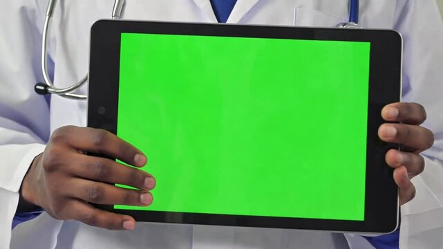 Doctor using tablet with green screen background. African American male doctor showing tablet to his colleague. Medical hospital professional using digital tablet computer. Health care copy space